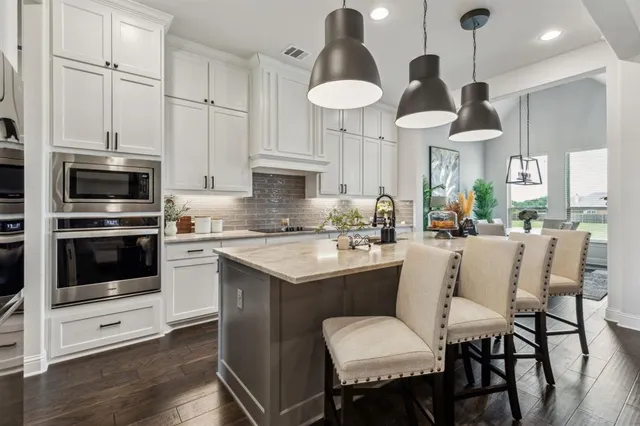 a kitchen with stainless steel appliances a dining table chairs stove and sink