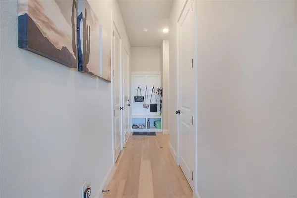 a view of a hallway with wooden floor and a bathroom