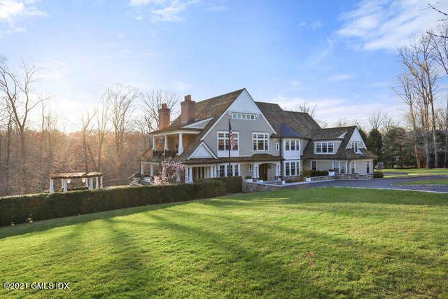 a view of a house with a big yard and large trees