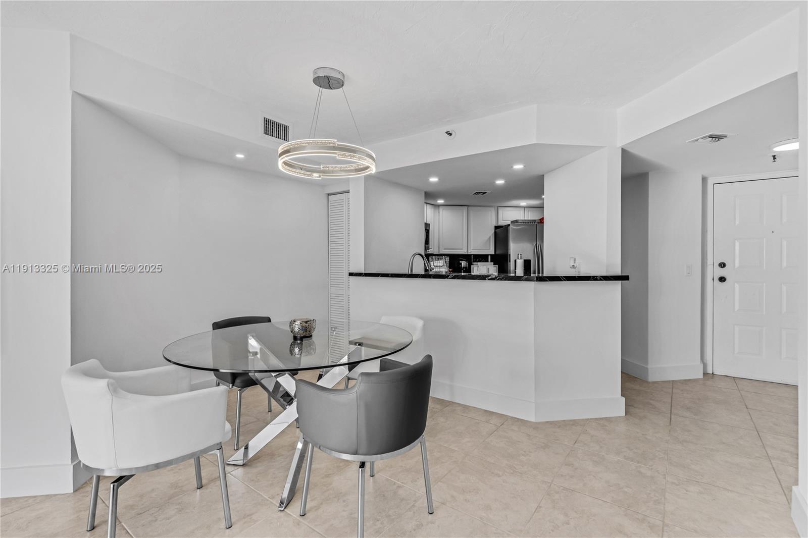 5880 Collins Avenue, Unit PH3 Miami Beach, FL 33140 - Photo 17 of 34 a kitchen with a dining table chairs and white cabinets