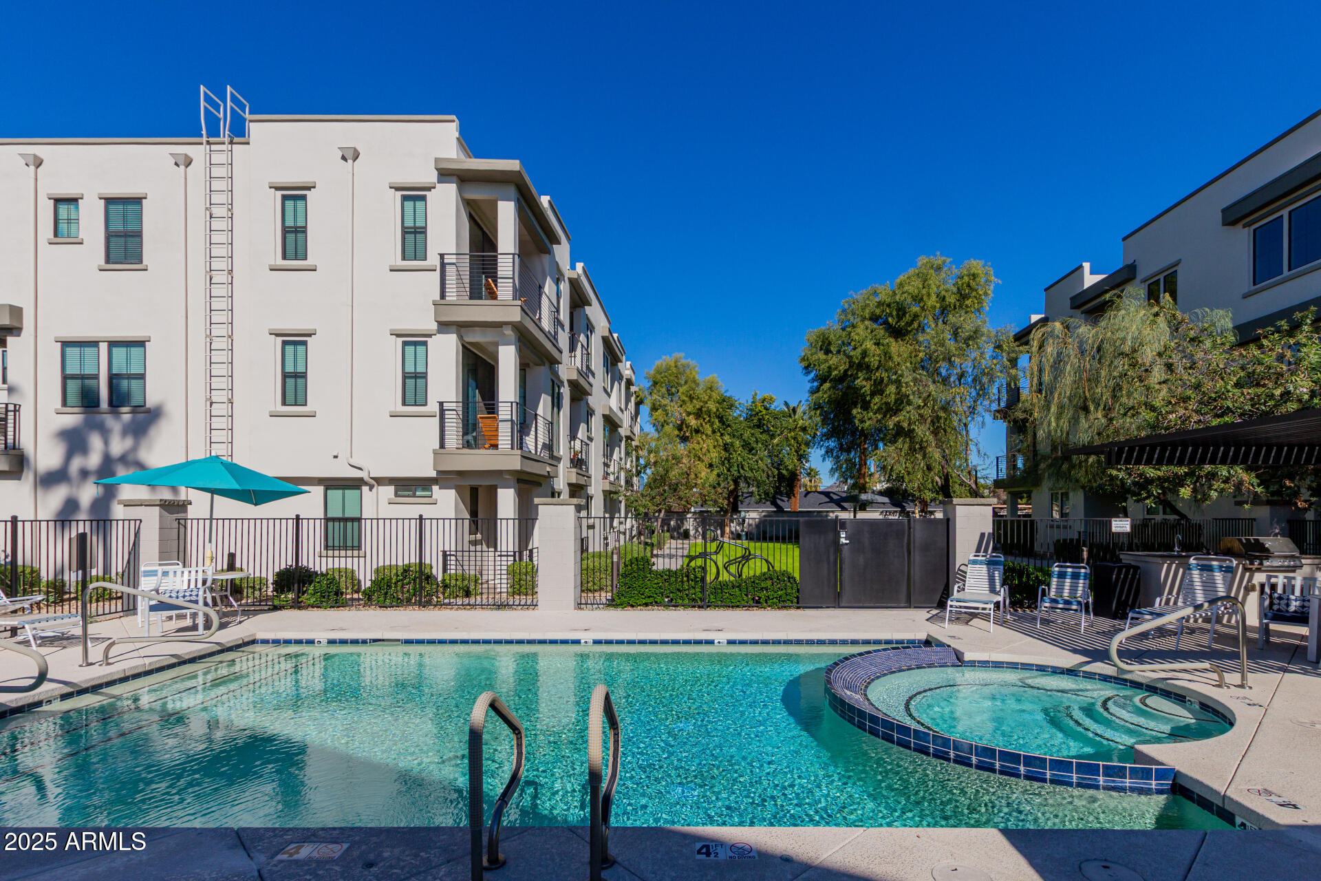 4235 North 26th Street, Unit 1 Phoenix, AZ 85016 - Photo 50 of 62 a view of a patio with couches table and chairs under an umbrella with a small swimming pool