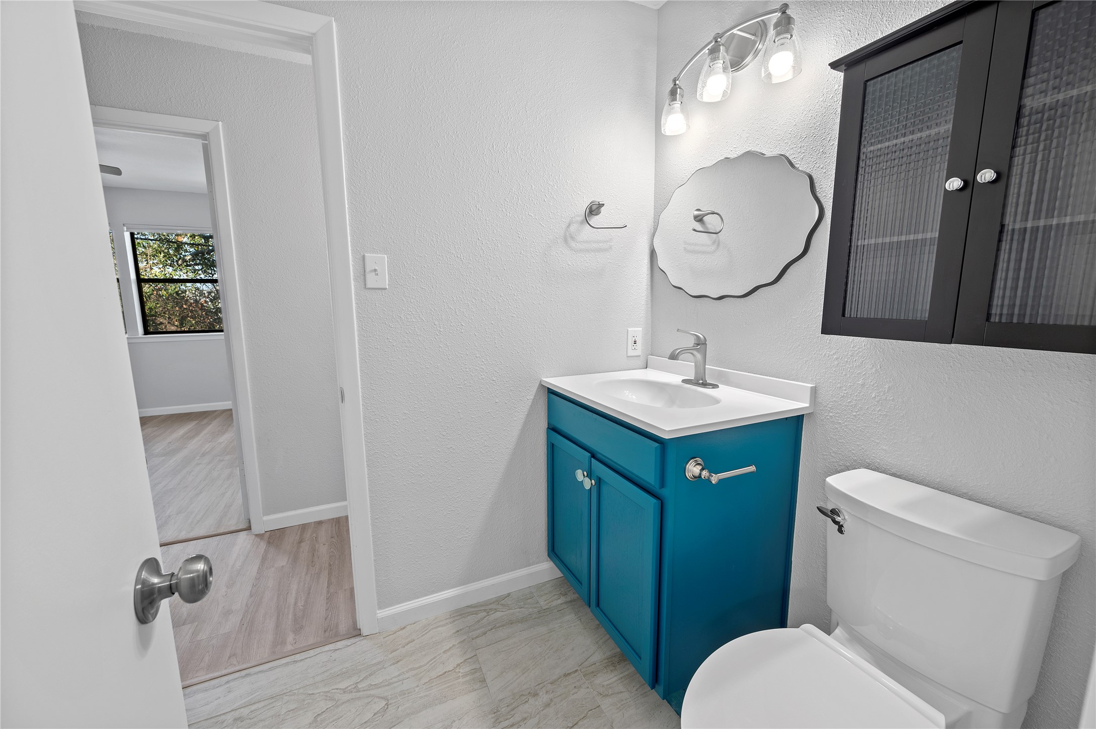 11301 Jollyville Road, Unit B3 Austin, TX 78759 - Photo 19 of 23 Half bathroom with vanity, a textured wall, and light marble finish flooring