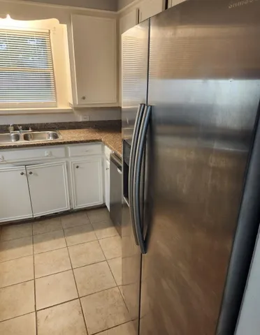 a kitchen with stainless steel appliances granite countertop a refrigerator a sink and white cabinets