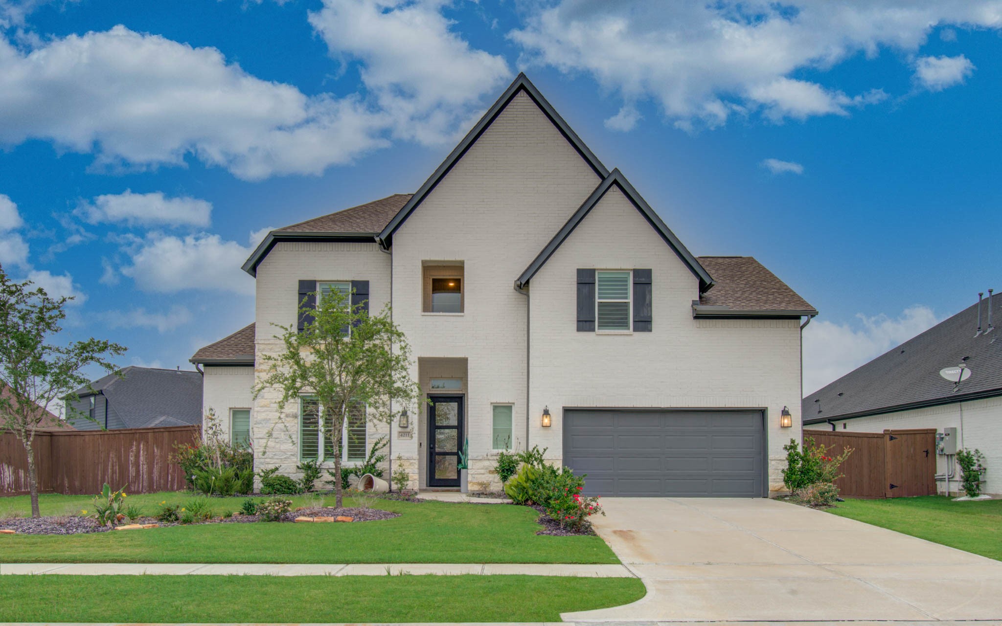 4211 Limestone Terrace Manvel, TX 77578 - Photo 1 of 33 This photo showcases a modern, two-story home with a white brick exterior and a steeply pitched roof. The house features a well-maintained lawn, a two-car garage, and a welcoming entrance with neat landscaping.