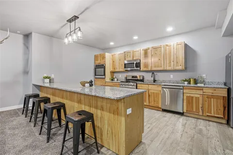 a kitchen with granite countertop a sink and dishwasher a stove top oven with wooden floor