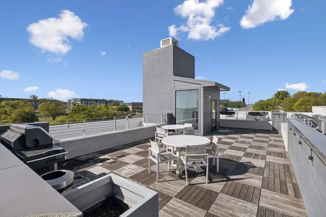 a roof deck with table and chairs and potted plants