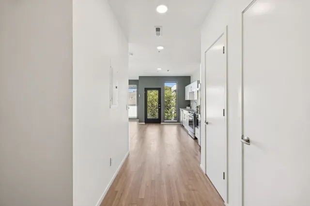 a view of a hallway with wooden floor and a bathroom