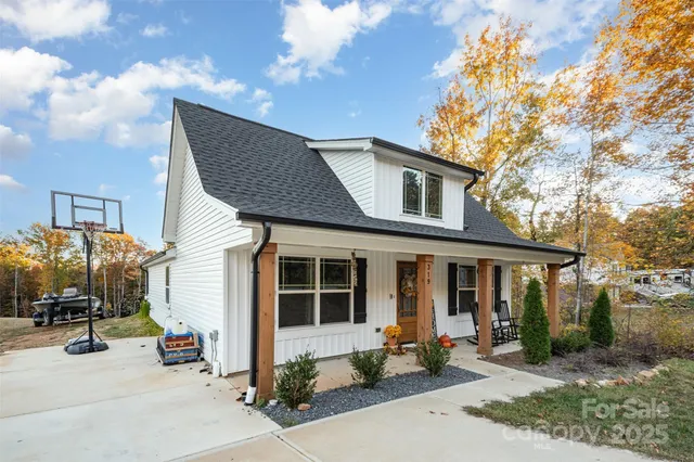 a view of backyard of house with outdoor seating and covered with trees
