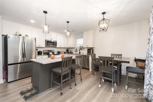 a kitchen with kitchen island a dining table chairs sink and stainless steel appliances