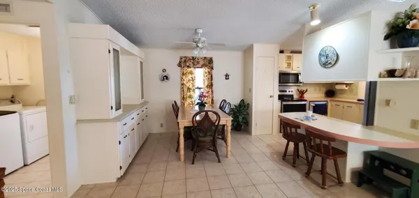 a kitchen with stainless steel appliances kitchen island granite countertop dining table chairs and a refrigerator
