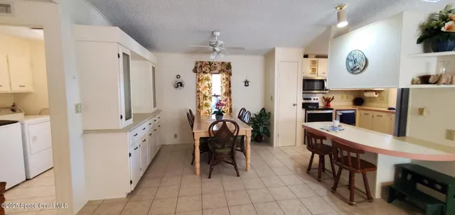a kitchen with stainless steel appliances kitchen island granite countertop dining table chairs and a refrigerator