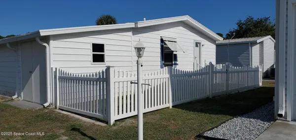 a view of a white house with a small yard and wooden fence