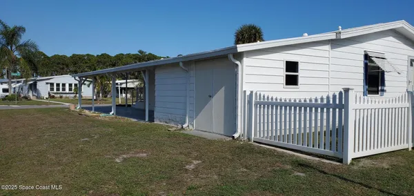 a view of a white house with a small yard and stairs