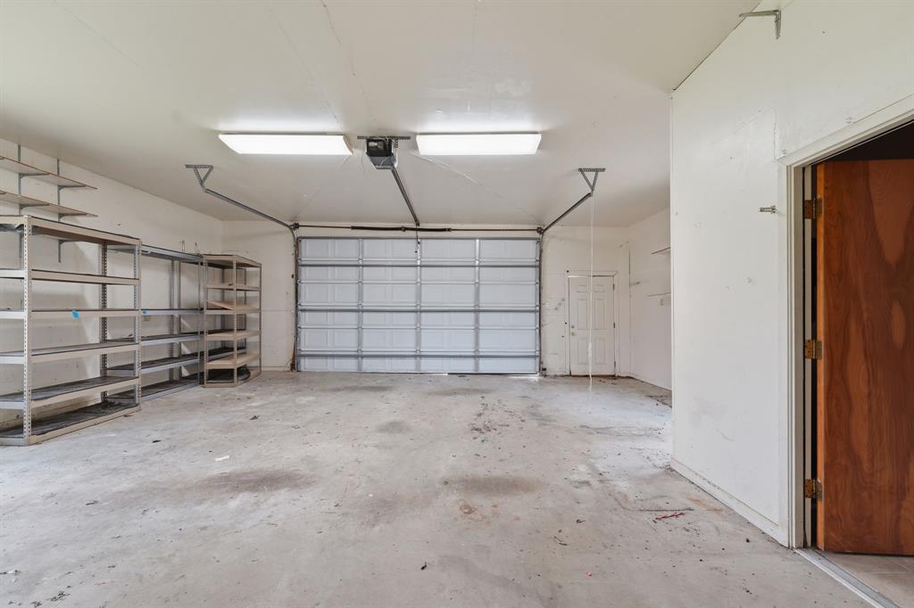 1235 Maxwell Road Haslet, TX 76052 - Photo 26 of 36 Spacious garage with overhead lighting, a sectional garage door, and built-in metal shelving