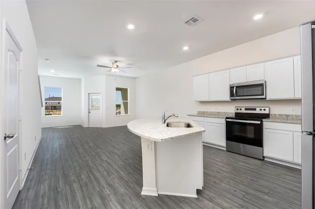 a kitchen with a sink stainless steel appliances and wooden floor