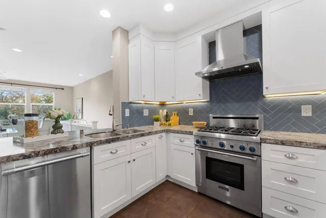 a kitchen with granite countertop white cabinets and stainless steel appliances