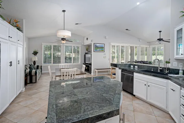 a large kitchen with granite countertop a stove a sink a dining table and chairs