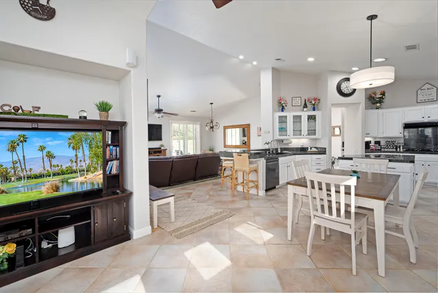 a view of a kitchen with kitchen island stainless steel appliances a stove a table and chairs