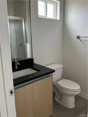 a bathroom with a granite countertop sink and a toilet