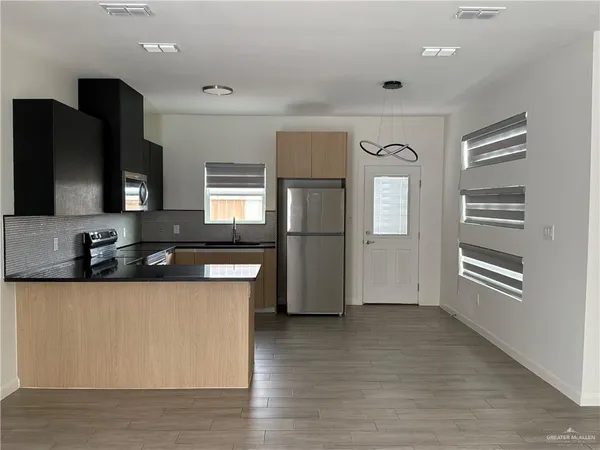 a kitchen with stainless steel appliances granite countertop a refrigerator a sink a stove and wooden floors