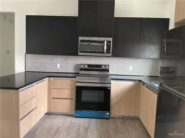 a kitchen with stainless steel appliances a stove a microwave and a hard wood floor