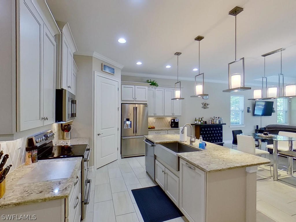 8920 Rails End Court Fort Myers, FL 33919 - Photo 4 of 35 a kitchen with stainless steel appliances kitchen island granite countertop a refrigerator a sink a stove and white cabinets with wooden floor