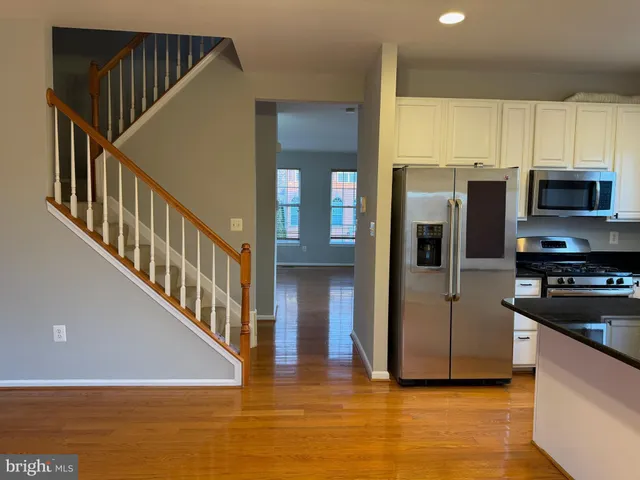 a view of a kitchen with a refrigerator a stove top oven a kitchen wooden floor and windows