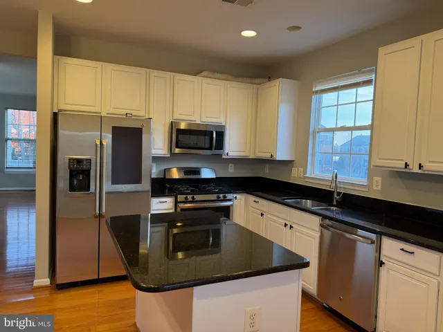 a kitchen with stainless steel appliances granite countertop a sink a stove cabinets and a refrigerator
