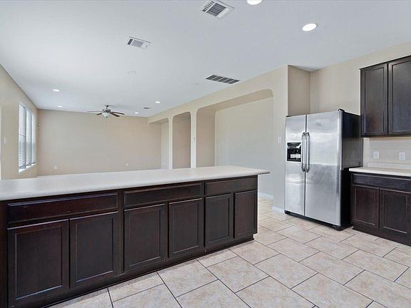 904 Lonesome Lilly Way Pflugerville, TX 78660 - Photo 7 of 34 The kitchen features dark wood cabinetry, light countertops, and a stainless steel refrigerator