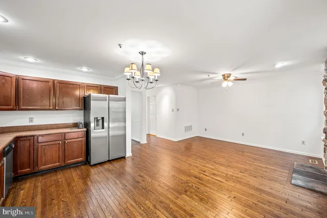 a view of a kitchen with stainless steel appliances wooden floor and chandelier