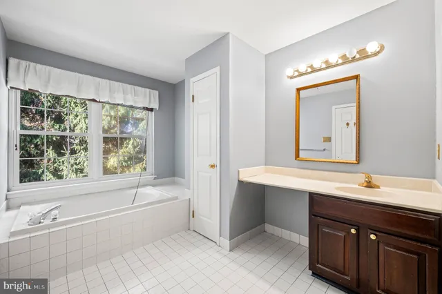 a bathroom with a tub sink and mirror