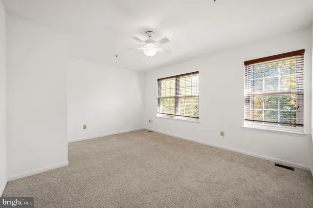 an empty room with a window and a ceiling fan