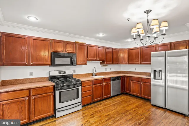a kitchen with stainless steel appliances granite countertop wooden cabinets a stove top oven a sink and dishwasher