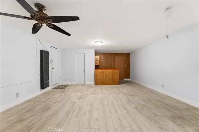 a view of empty room with wooden floor and ceiling fan