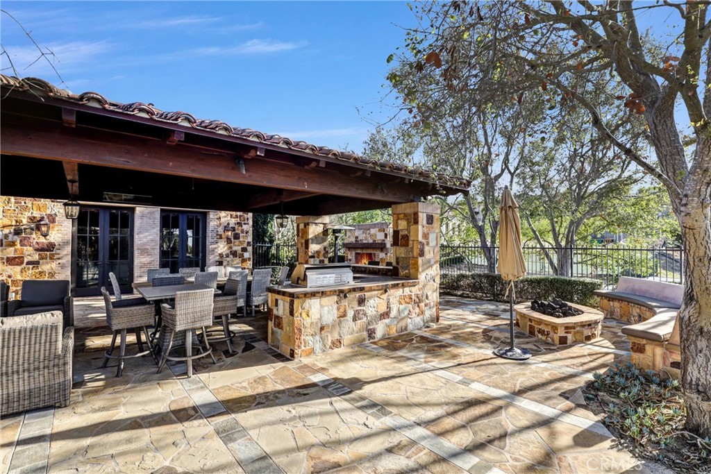 41 Needle Grass Irvine, CA 92603 - Photo 52 of 64 a view of a patio with table and chairs under an umbrella with a large tree