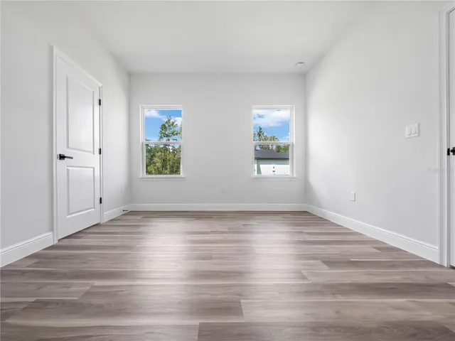 a view of an empty room with wooden floor and window