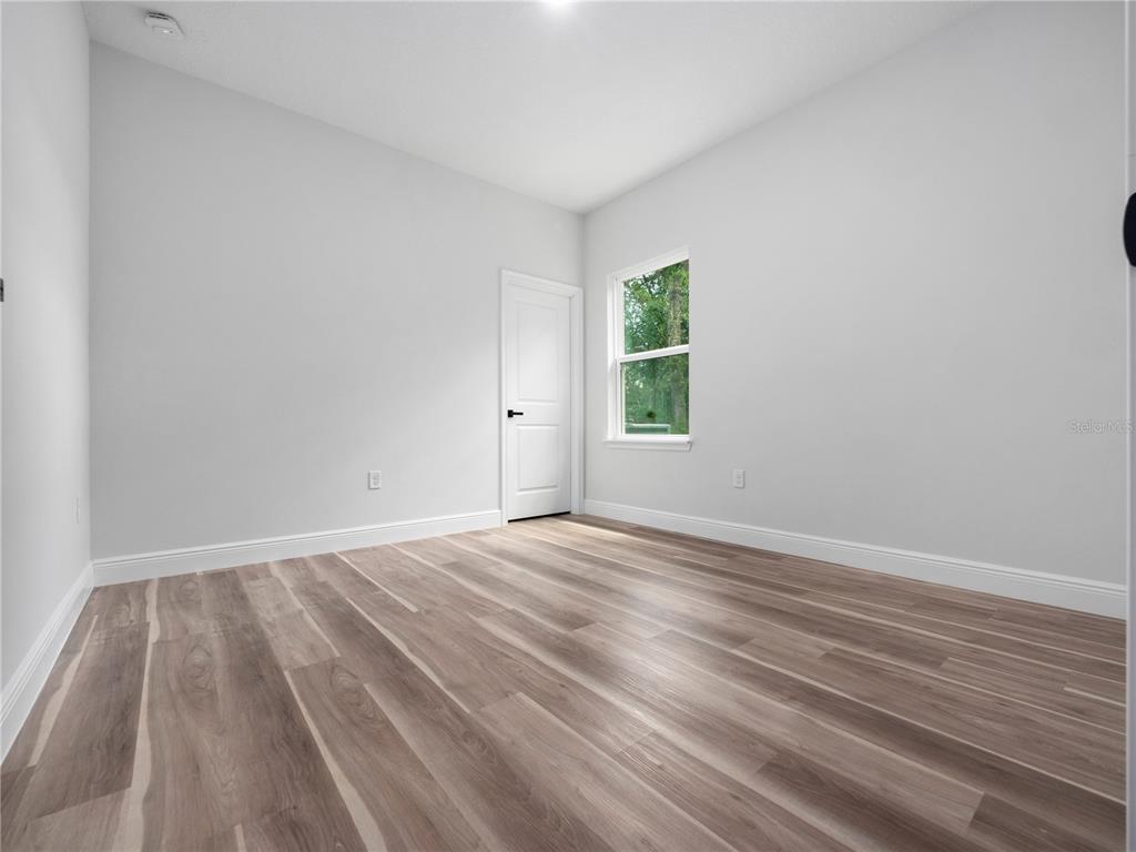 3310 Southwest 177th Lane Road Ocala, FL 34473 - Photo 19 of 40 a view of an empty room with wooden floor and a window