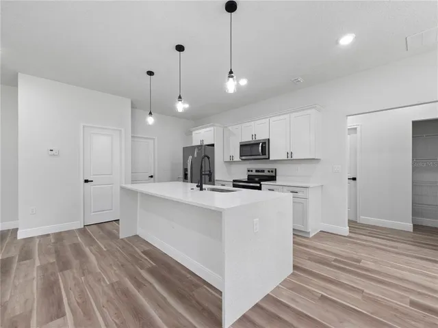 a kitchen with stainless steel appliances kitchen island a refrigerator sink and cabinets