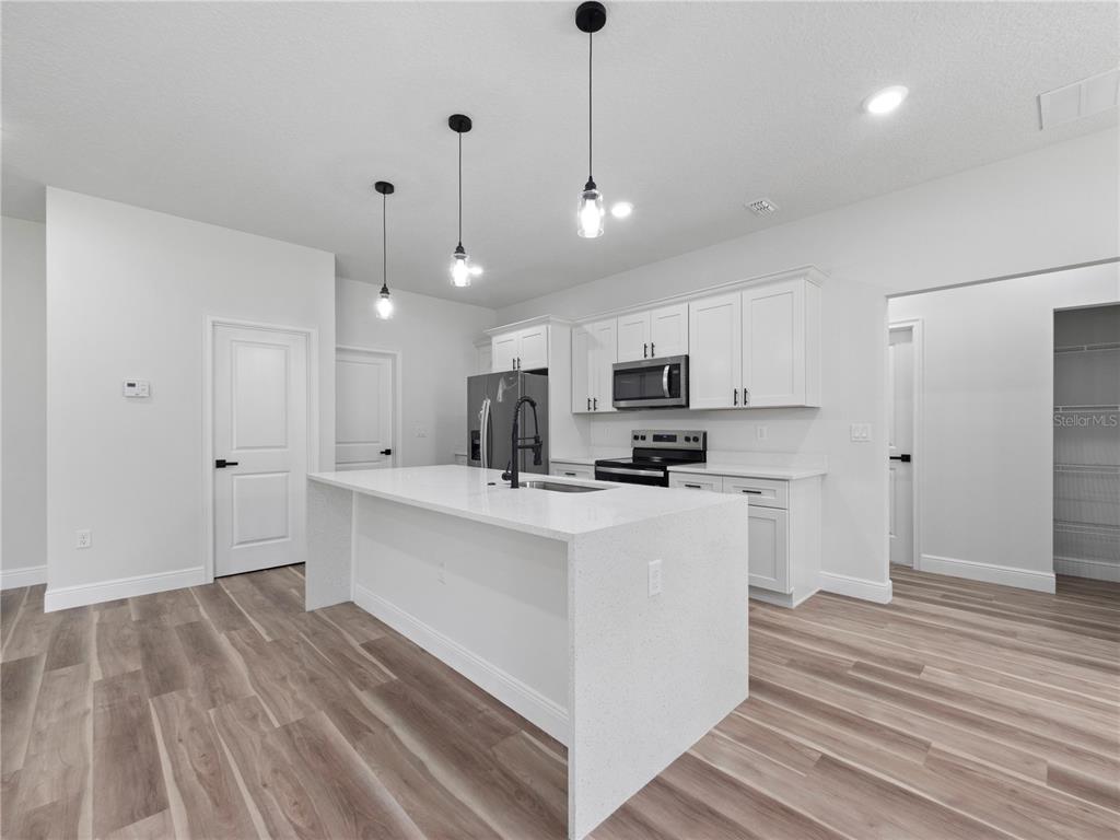 3310 Southwest 177th Lane Road Ocala, FL 34473 - Photo 25 of 40 a kitchen with stainless steel appliances kitchen island a refrigerator sink and cabinets