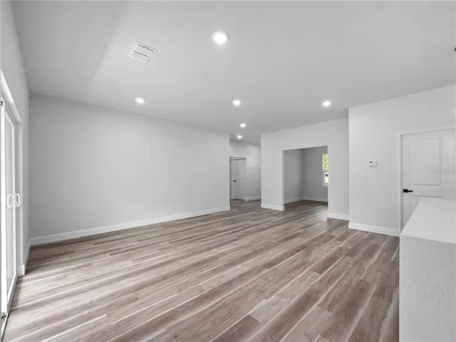 an empty room with wooden floor and natural light