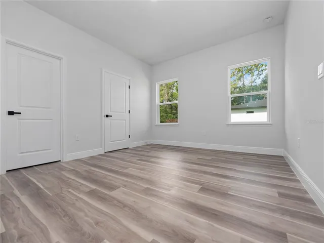 a view of an empty room with wooden floor and window