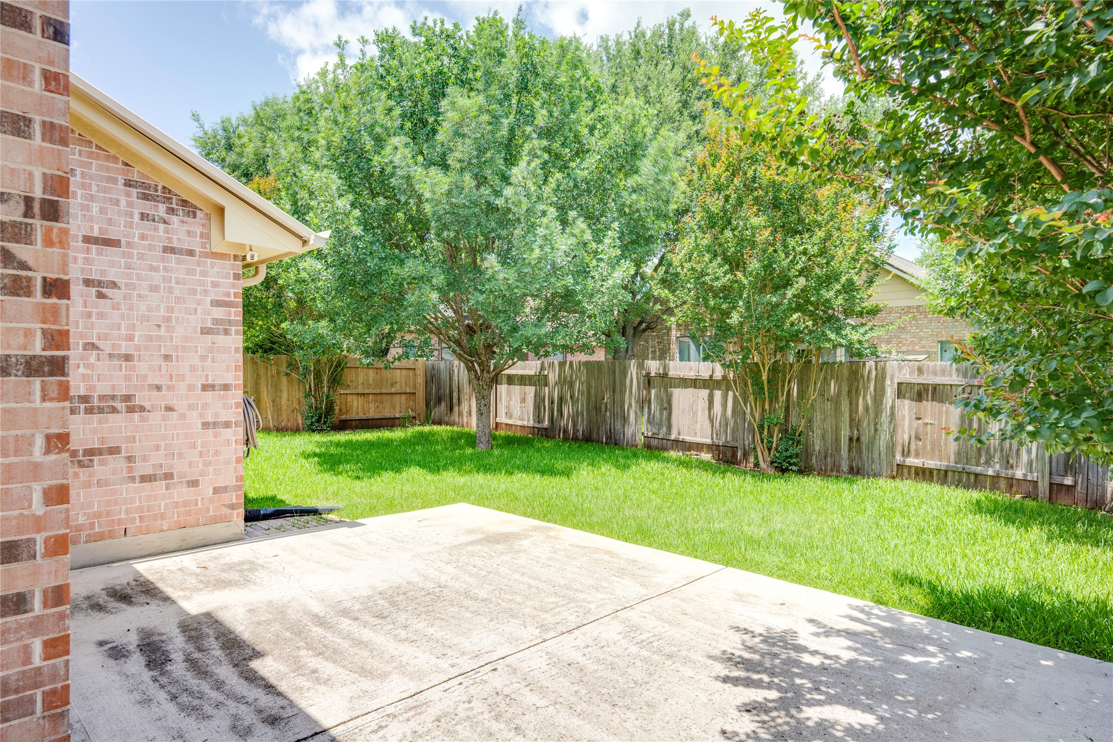 1813 Nelson Ranch Loop Cedar Park, TX 78613 - Photo 30 of 39 A spacious concrete patio opens to a vibrant, private backyard bordered by a natural wood fence and mature trees.