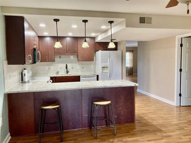 a kitchen with stainless steel appliances kitchen island a table chairs in it and wooden floors