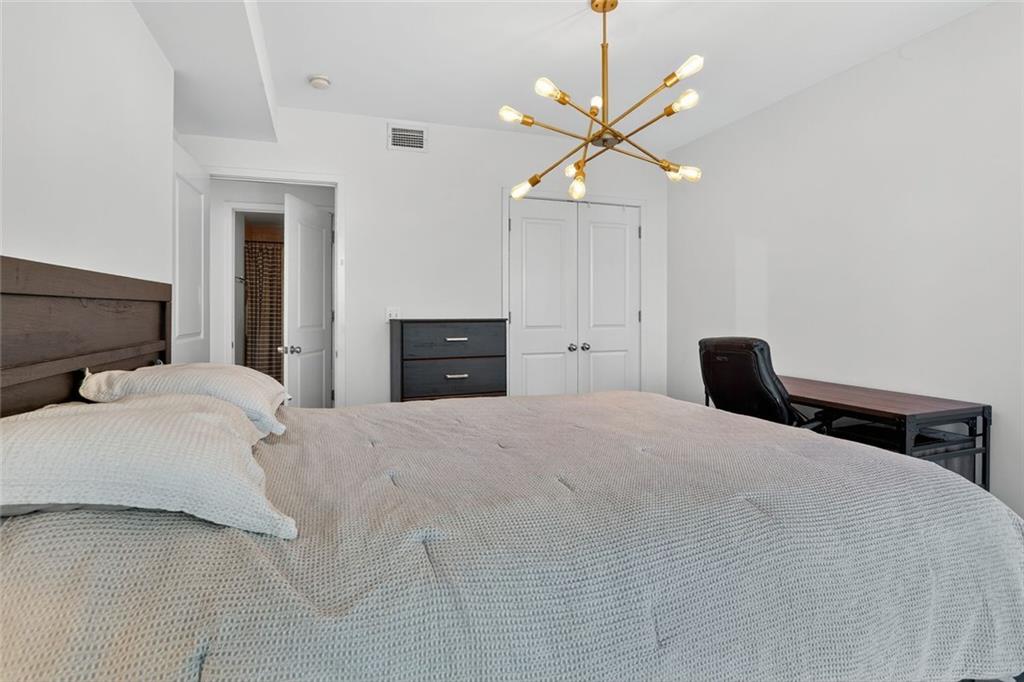 3338 Peachtree Road Northeast, Unit 1706 Atlanta, GA 30326 - Photo 12 of 35 a bedroom with a large bed and a chandelier