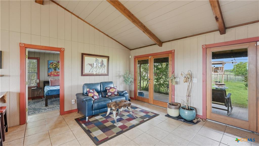 127 Offer Llano, TX 78643 - Photo 12 of 40 Vaulted ceiling with exposed wood beams, tile flooring, and multiple exterior glass doors