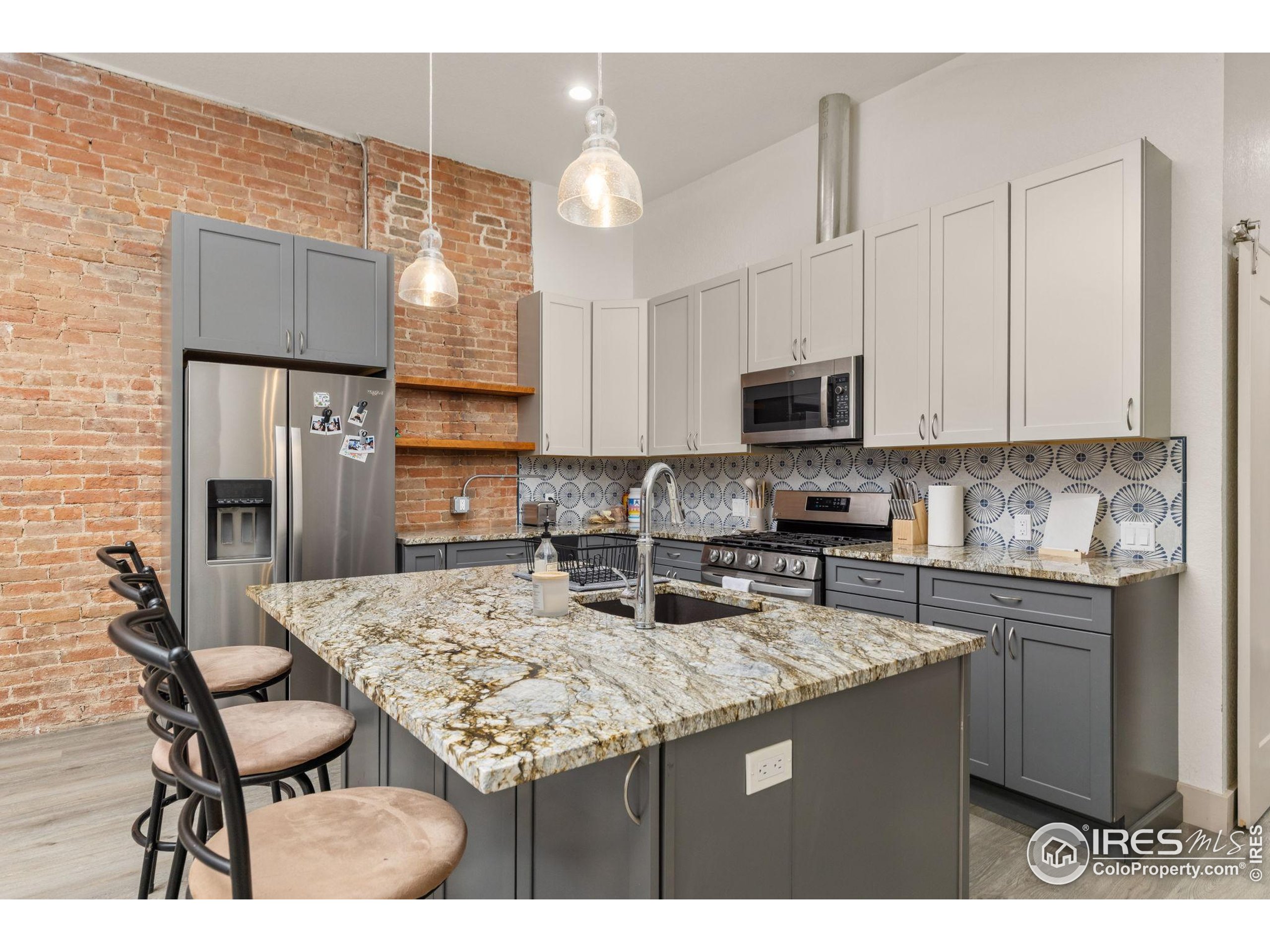 331 Main Street Longmont, CO 80501 - Photo 31 of 50 a kitchen with kitchen island granite countertop a stove top oven a sink a counter space and cabinets