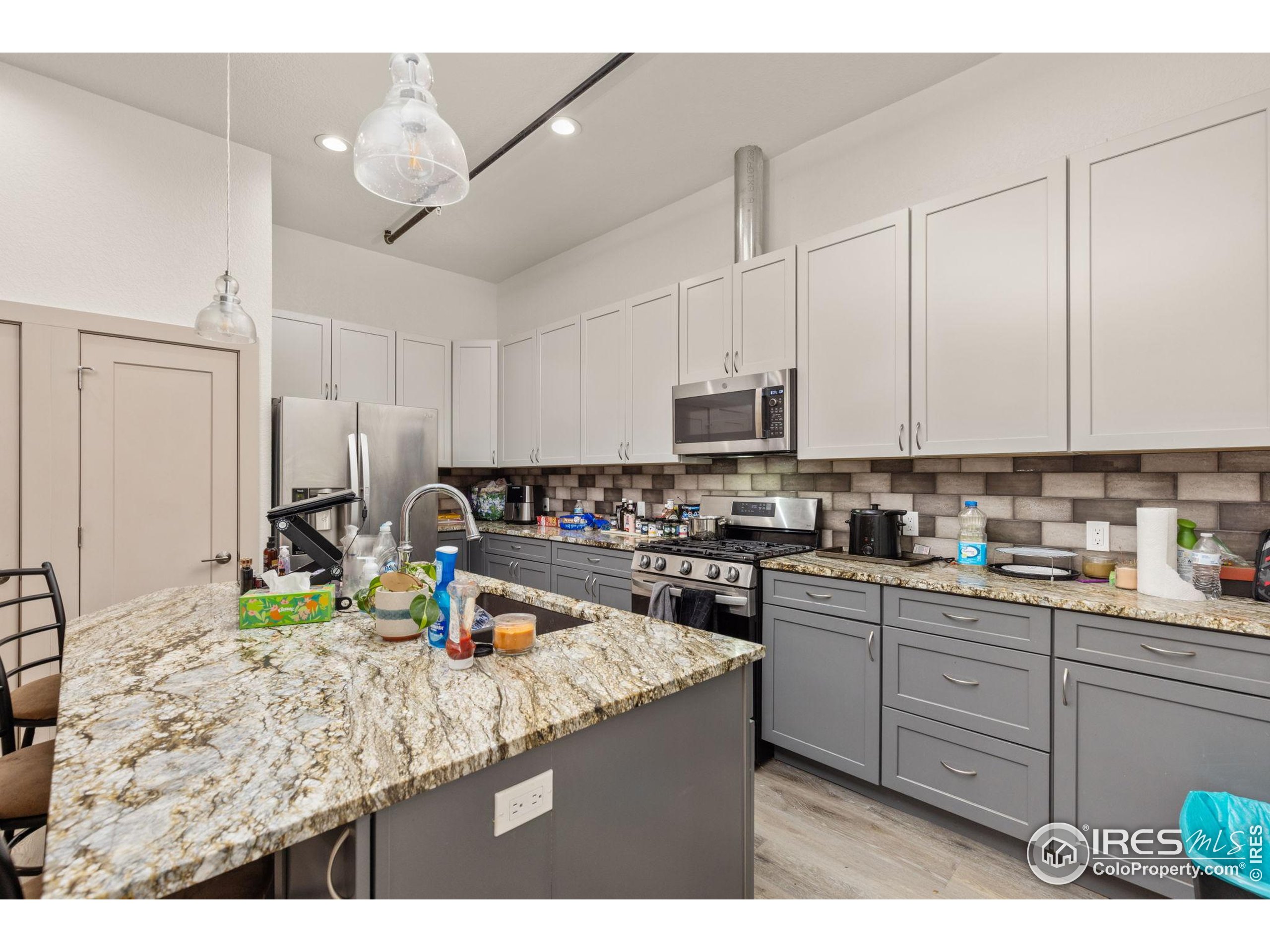 331 Main Street Longmont, CO 80501 - Photo 40 of 50 a kitchen with kitchen island granite countertop a sink cabinets and stainless steel appliances