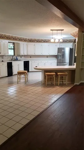 a large kitchen with stainless steel appliances a stove and white cabinets