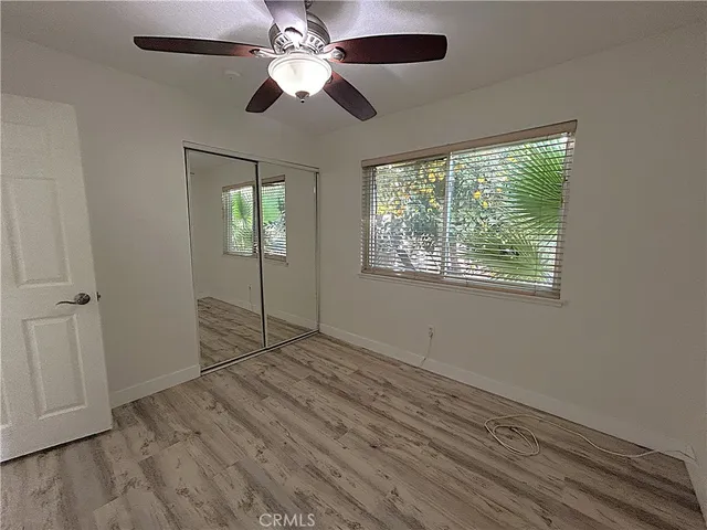 an empty room with wooden floor chandelier fan and windows
