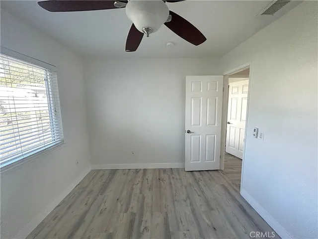 an empty room with wooden floor cabinet and windows